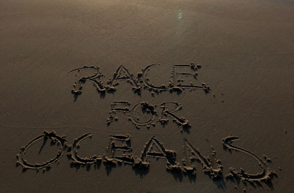 Race for Oceans written in sand