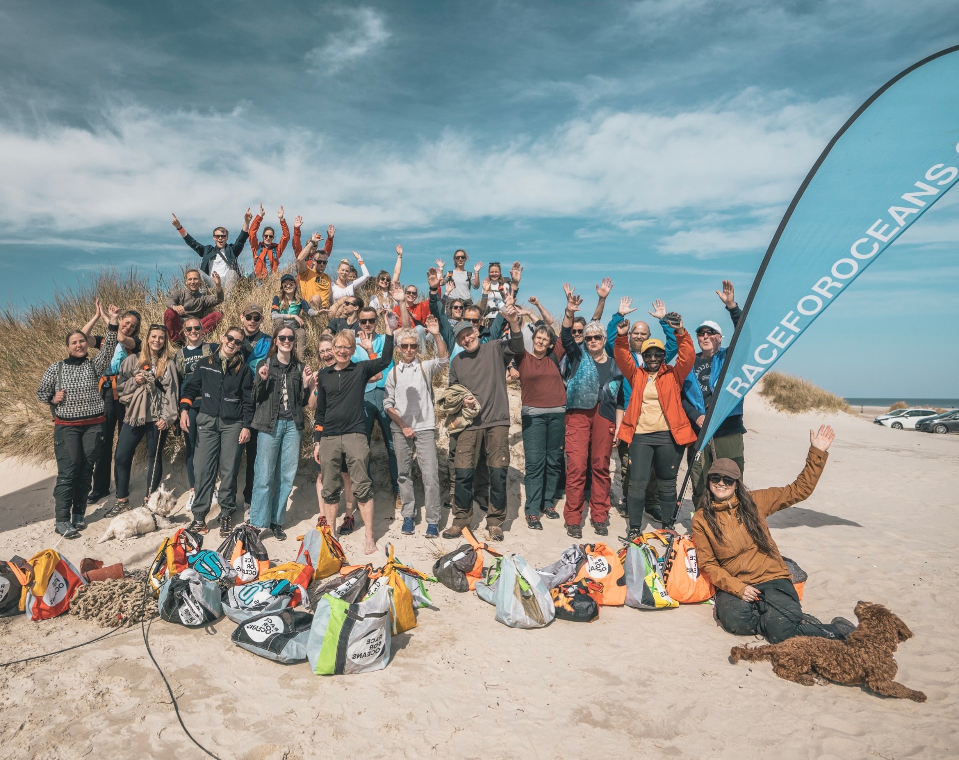 A group of volunteers at a Race for Oceans beach cleanup with collected bags of plastic waste